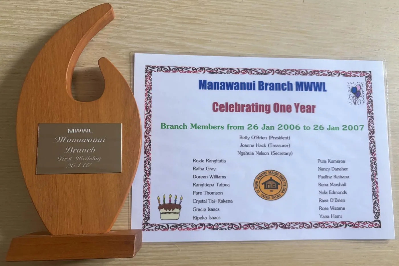 Wooden trophy beside a certificate titled "Manawanui Branch MWWL Celebrating One Year" listing branch members from 26 Jan 2006 to 26 Jan 2007.