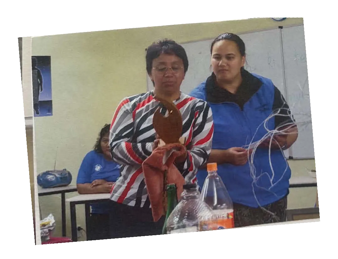 Two women examining the wooden trophy together in a meeting room.