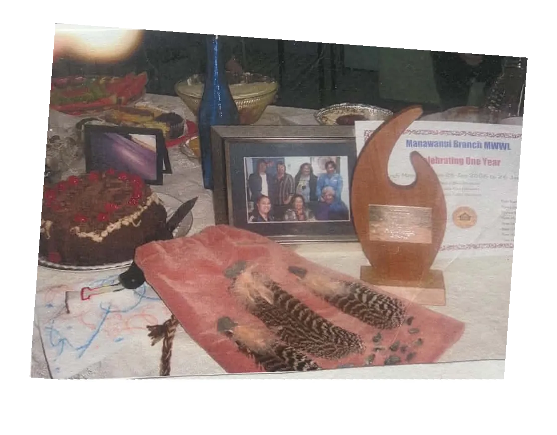 Display table with the wooden trophy, a chocolate cake, a framed photo and a feathered cloth.