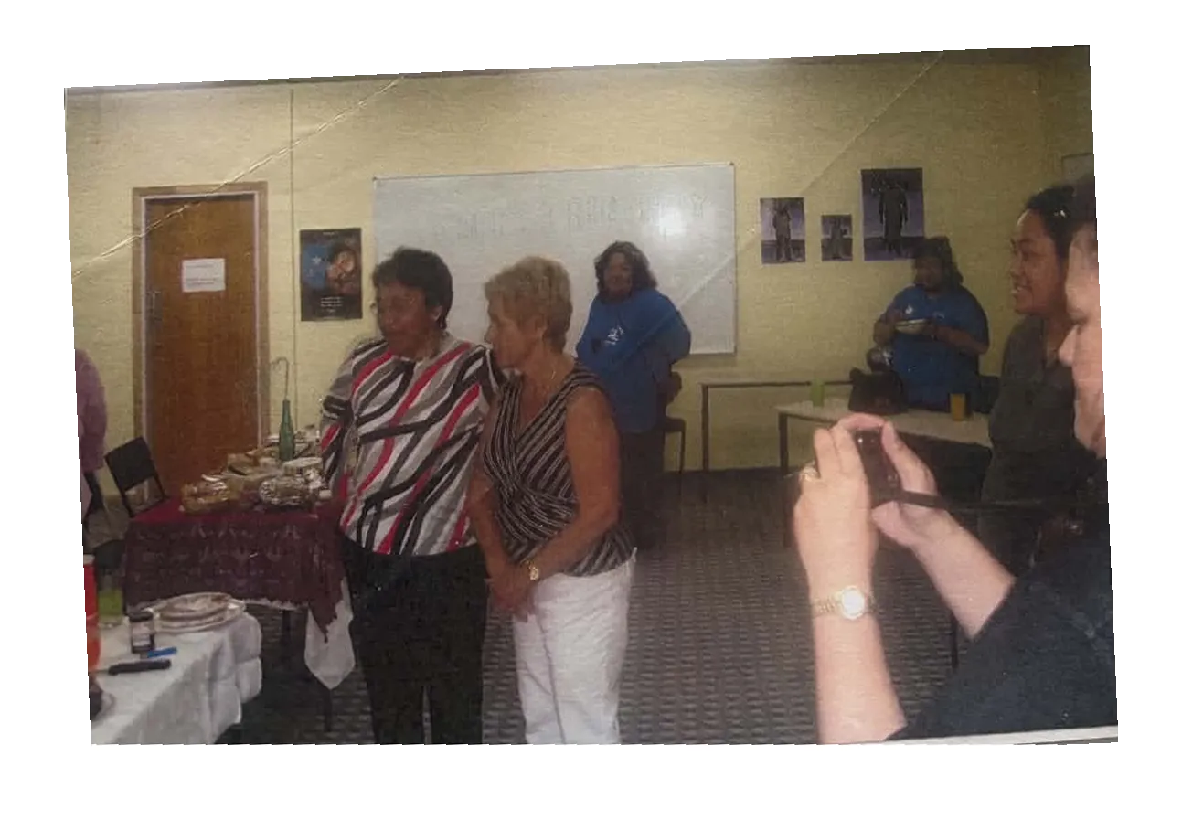 Members standing in a hall near a buffet table while a guest takes a photo.