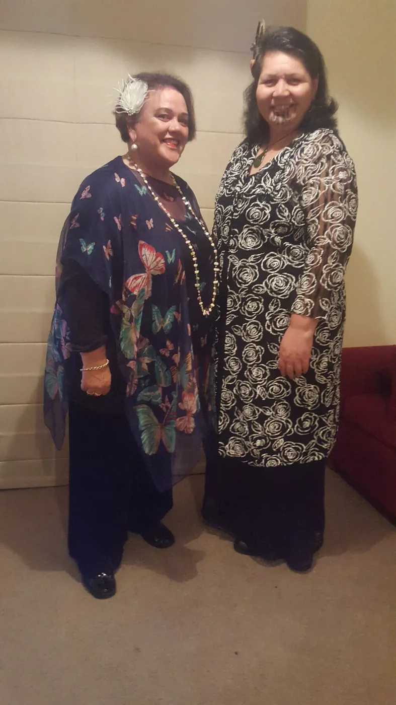 Two women in formal dresses standing side by side.