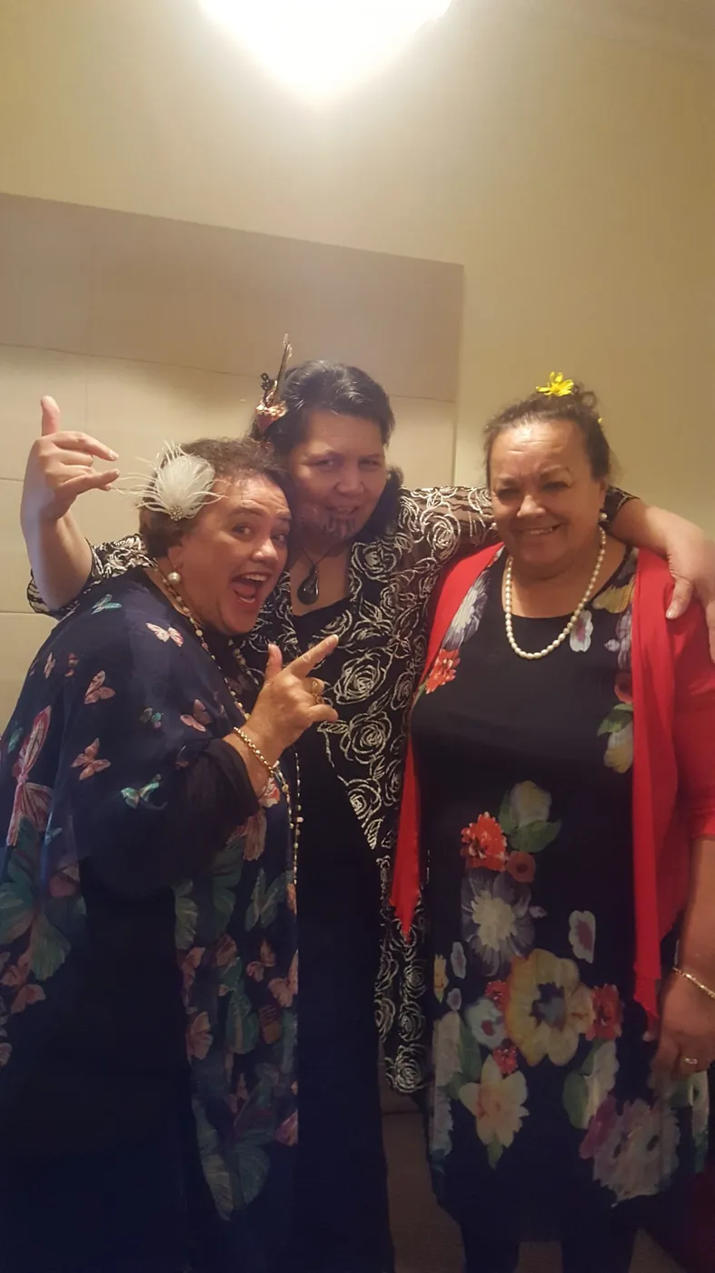Three women in floral outfits posing playfully together indoors.