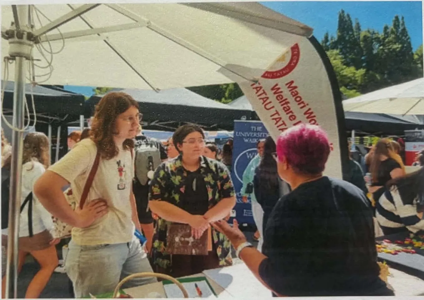 Woman talking with students under a gazebo at an outdoor orientation event.