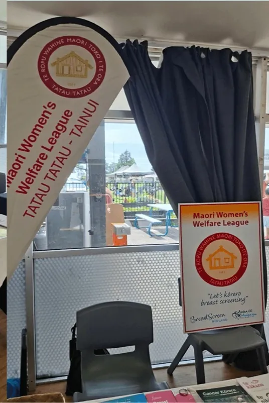 League banner and a sign standing beside blue curtains in a community hall.