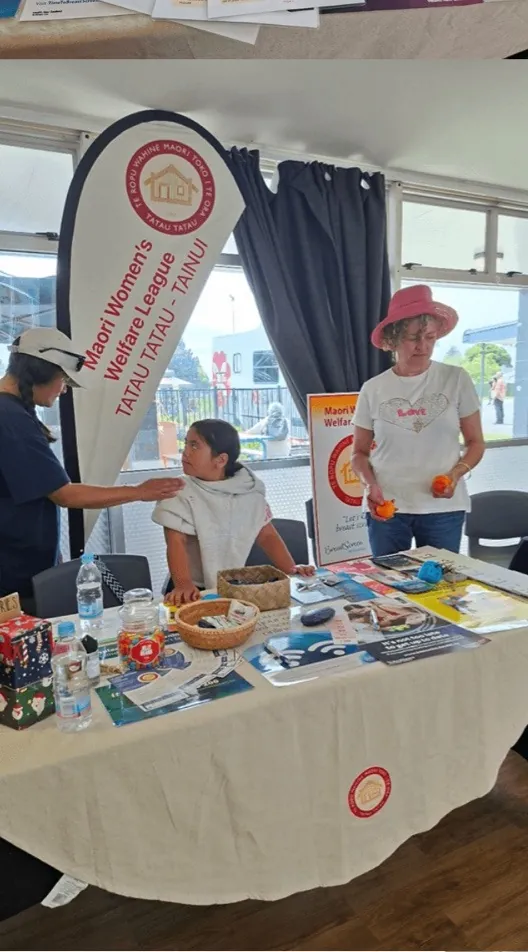 Members standing at a stall table beside a League banner.