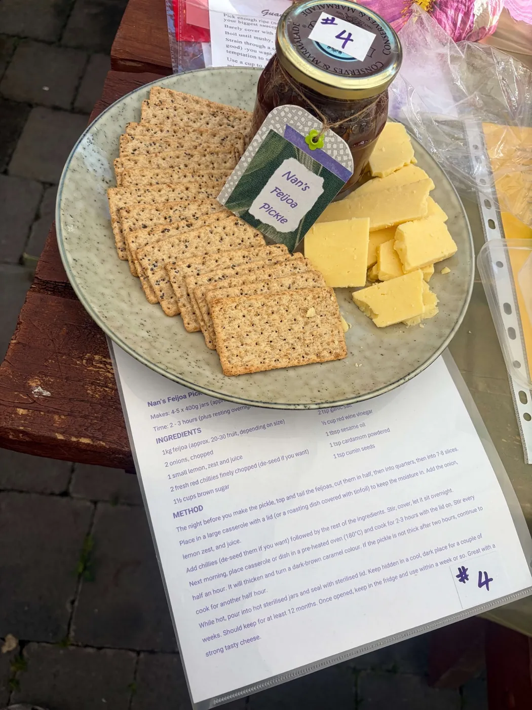 Plate of crackers and cheese beside a numbered jar of chutney, above a printed entry sheet.