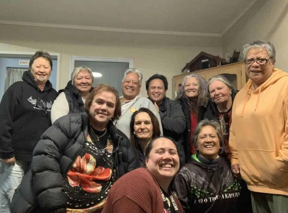 A group of people crowded together for a smiling group photo, indoors.